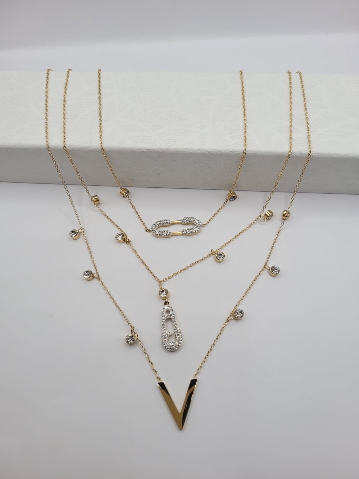 rédige moi un article qui vente le design et le style du Collier Triples Chaines avec Trois Pendentifs Doré et Strass pour une boutique de bijoux en ligne